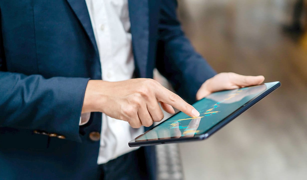 Person im Anzug, die ein Tablet bedient und mit einer Finanzgrafik auf dem Bildschirm interagiert